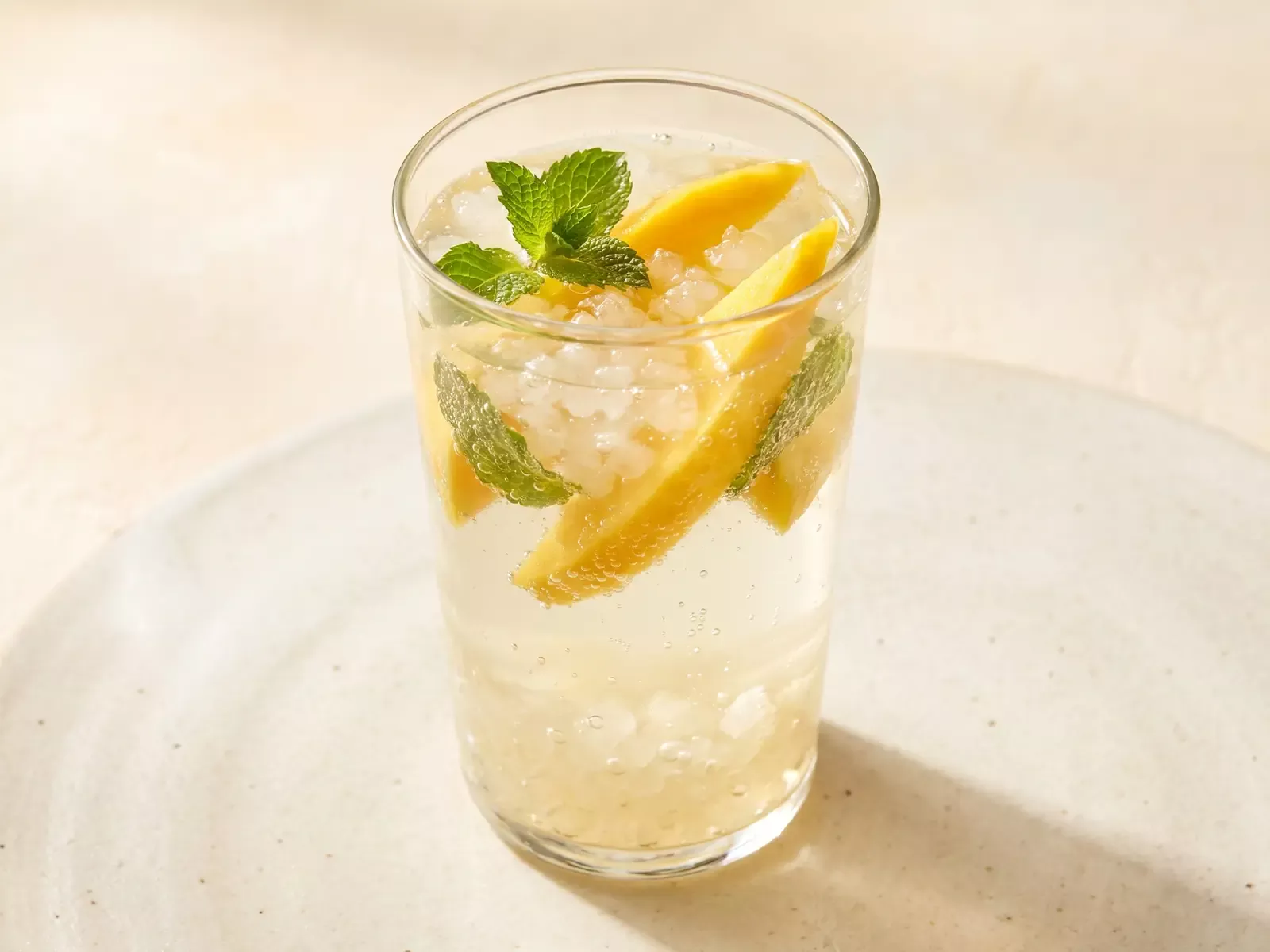 Verre de k&eacute;fir d&rsquo;eau avec mangue et menthe, servi sous une lumi&egrave;re chaude et douce.