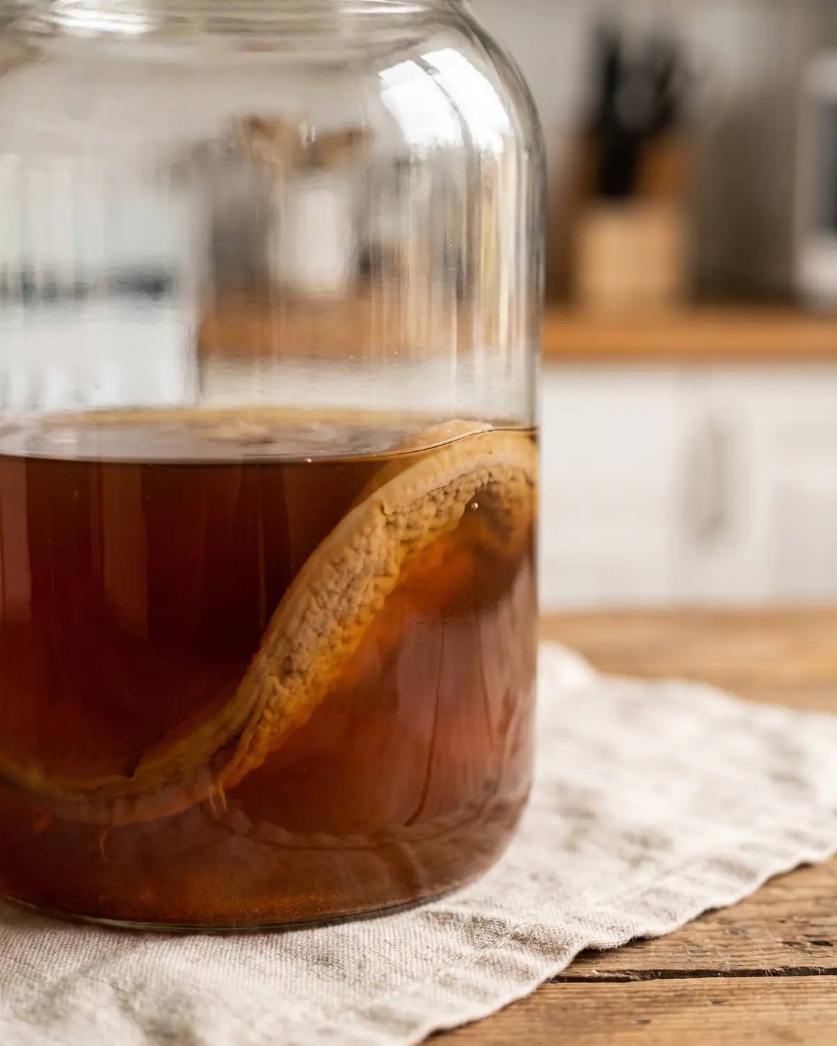 difference kefir kombucha Détail ambré d’un bocal de kombucha, avec le SCOBY beige effleurant la surface du liquide.