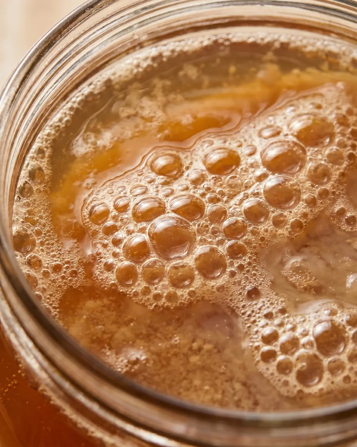 conservation kombucha Macro de bulles fines à la surface d’un kombucha ambré dans un verre partiellement cadré